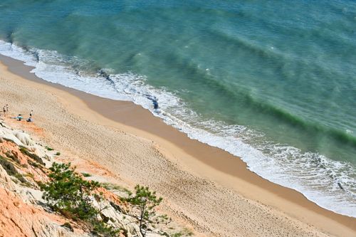 Free Aerial view of Albufeira beach in Portugal with waves hitting the sandy shore and cliffs. Stock Photo