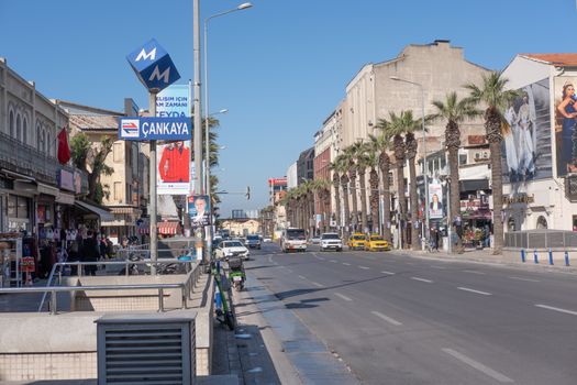 Explore a bustling street in İzmir with palm trees, shops, and urban life.