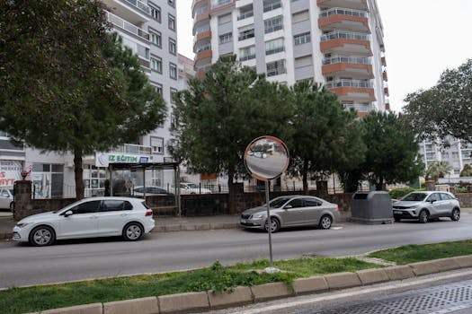 City street in İzmir with modern buildings and parked vehicles.