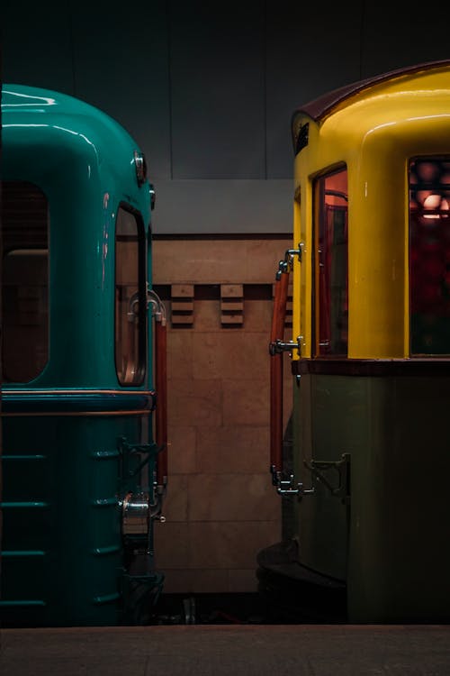 Two colorful trains sitting next to each other in a dark room