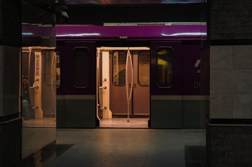 A purple train with doors open in a subway station