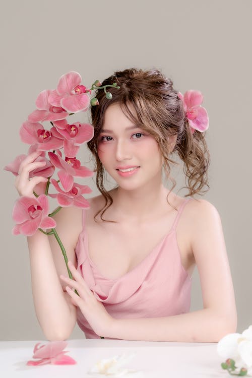 A woman in pink dress holding a bunch of flowers