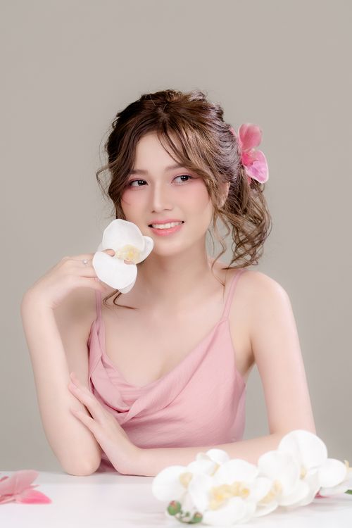 Free Elegant portrait of a smiling woman holding white flowers indoors. Stock Photo