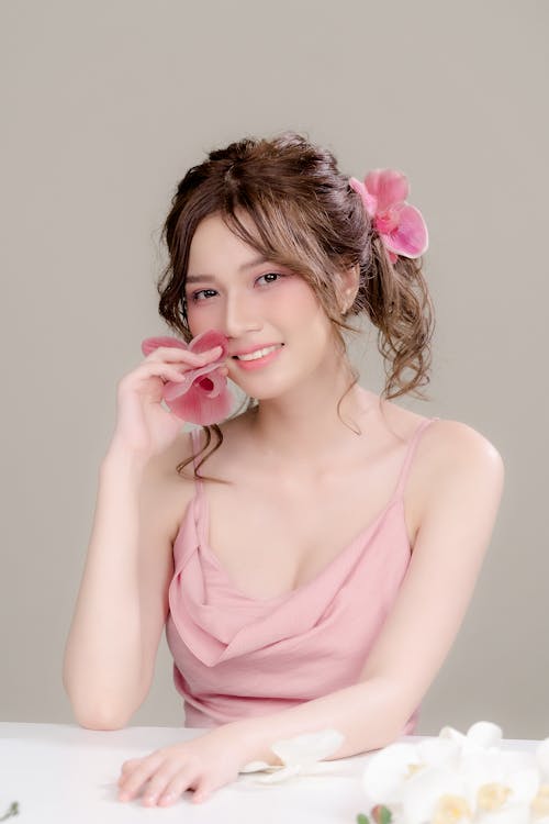 A woman in a pink dress holding a flower