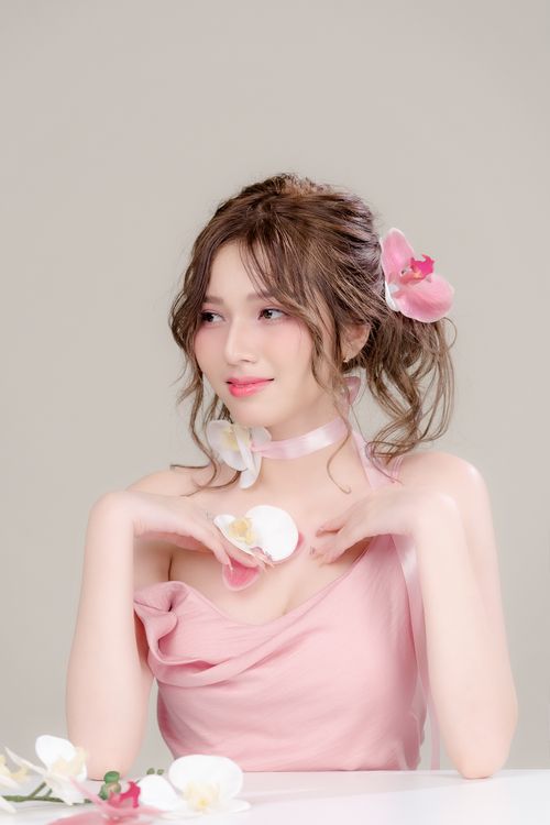 Free Beautiful portrait of woman in pink with orchids, exuding grace and elegance. Stock Photo