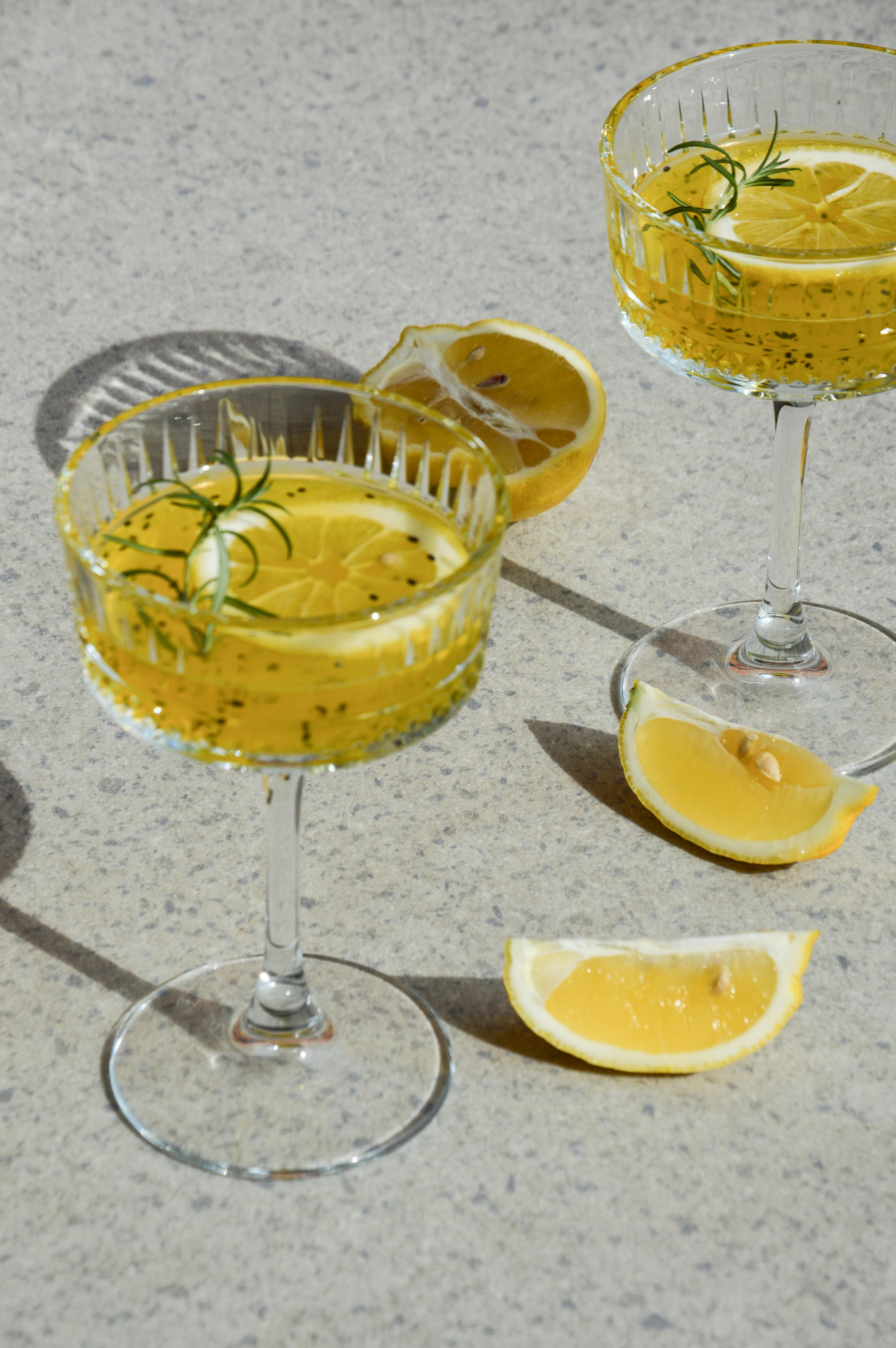 Elegant citrus drinks in crystal glasses with fresh lemon slices and rosemary.