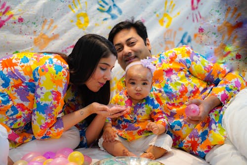 A family is sitting on the floor with colorful paint on their hands