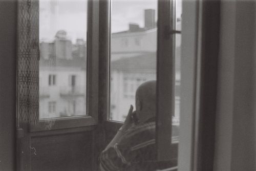 Free Bald man sitting by a window in a black and white urban scene, contemplative mood. Stock Photo