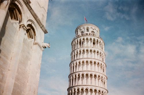 Free Leaning Tower of Pisa captured from a low angle, highlighting its distinct architecture against a blue sky. Stock Photo