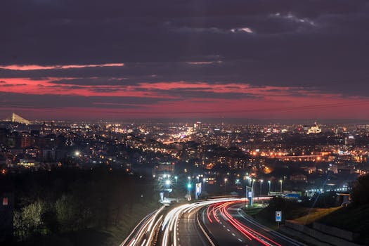 A vibrant cityscape at night featuring light trails and illuminated landmarks.