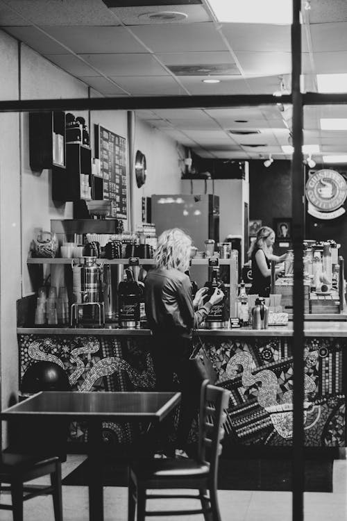 Photo En Niveaux De Gris D'une Femme Debout Près Du Comptoir