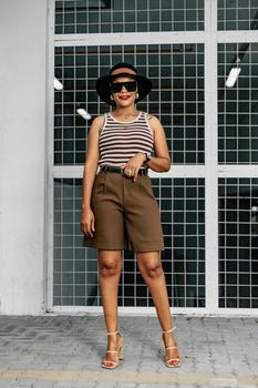 Stylish woman in urban attire posing confidently outdoors, showcasing modern fashion elements.