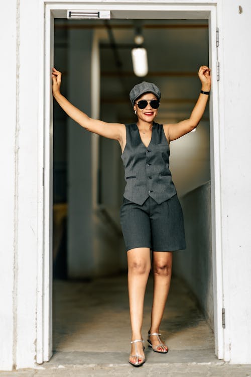A woman in a hat and sunglasses standing in an open door
