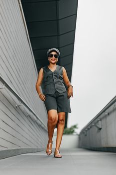Confident woman in stylish outfit walking outdoors in urban environment.