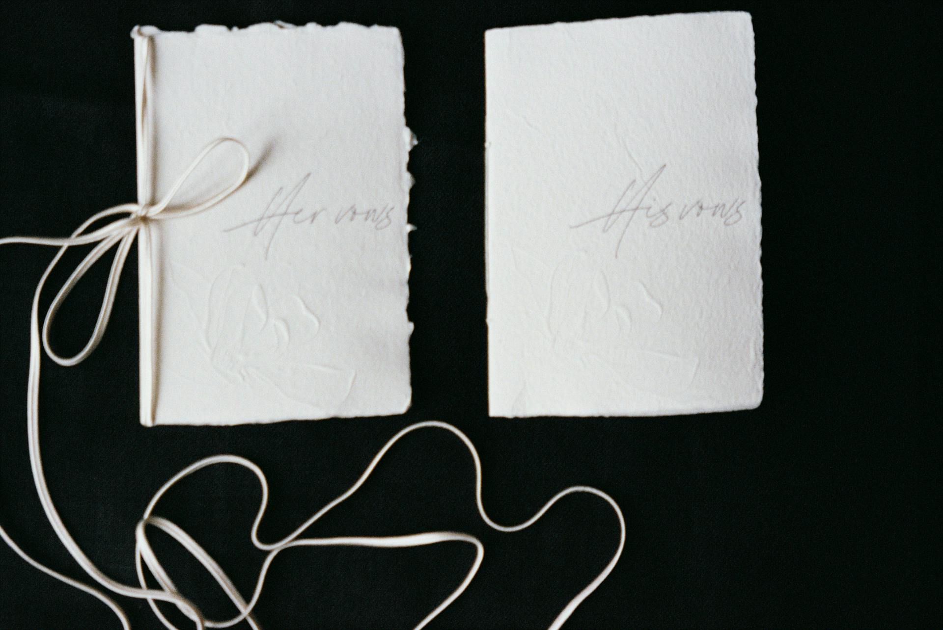 Stylish handmade invitation cards with subtle text on a black background, tied with ribbon.