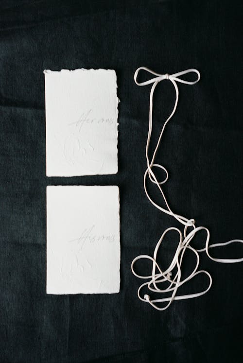 Two white paper cards with string tied to them