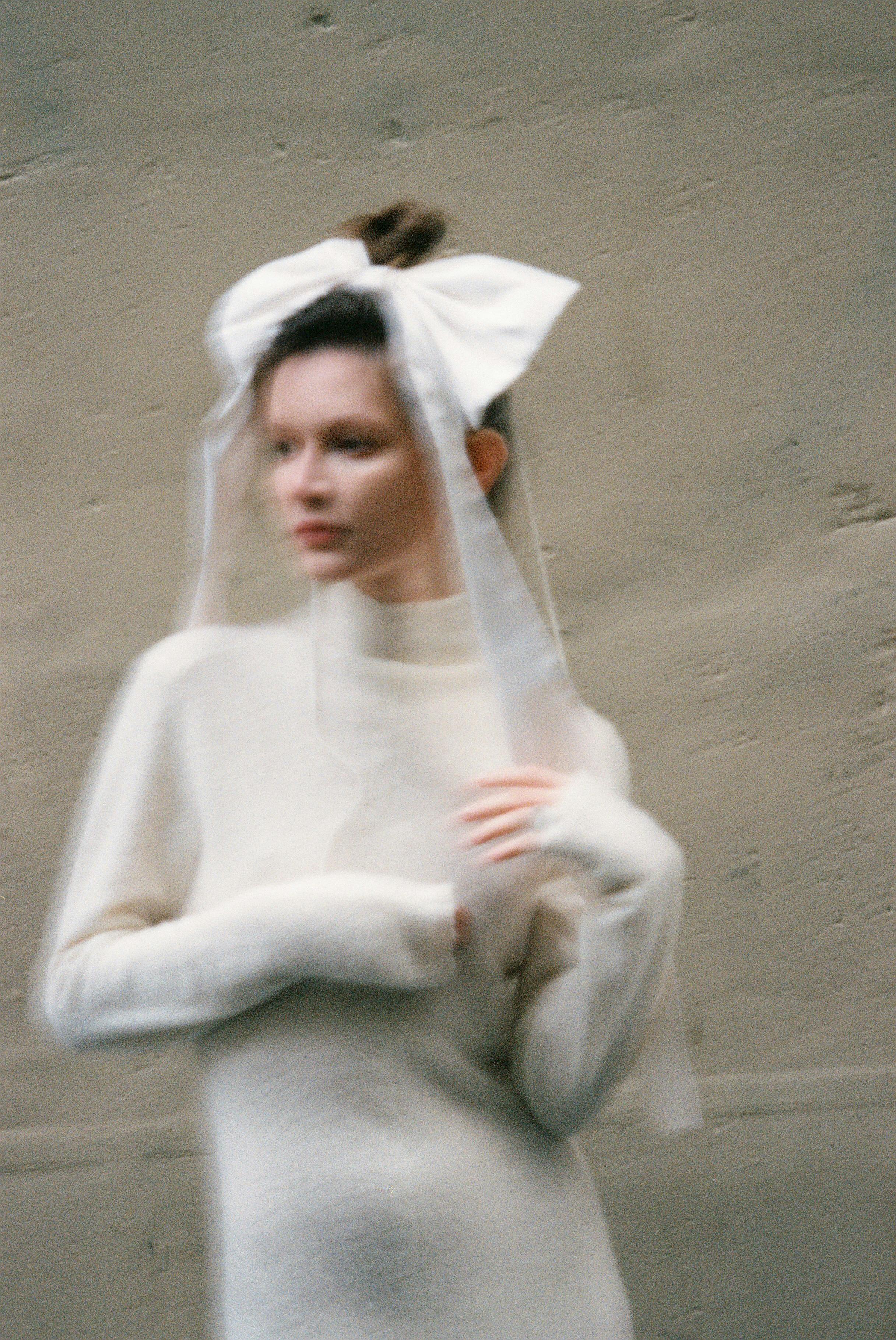 A blurred portrait of a woman with a large bow, conveying elegance and softness.