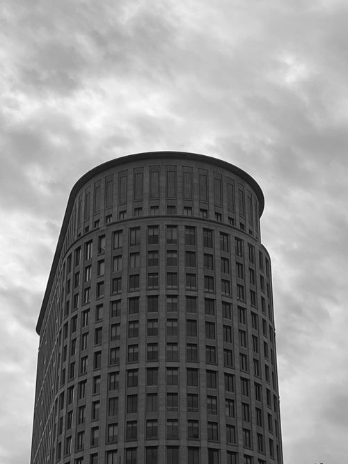 Free Dramatic black and white view of a modern skyscraper against cloudy skies. Stock Photo