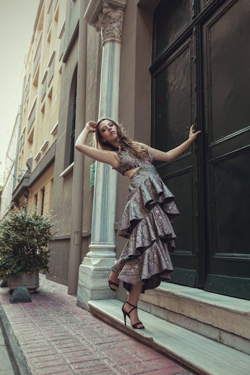A woman in a dress is leaning against a building