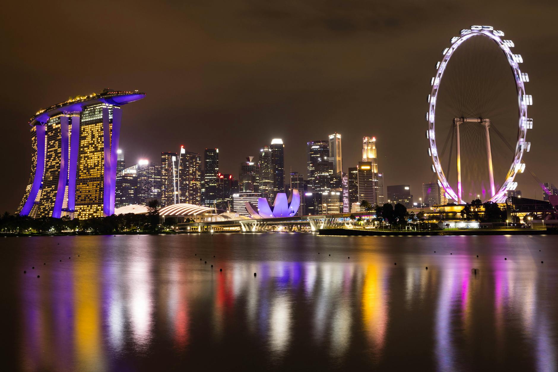 Singapore skyline at night featuring Marina Bay Sands and Singapore Flyer reflecting on the water.
