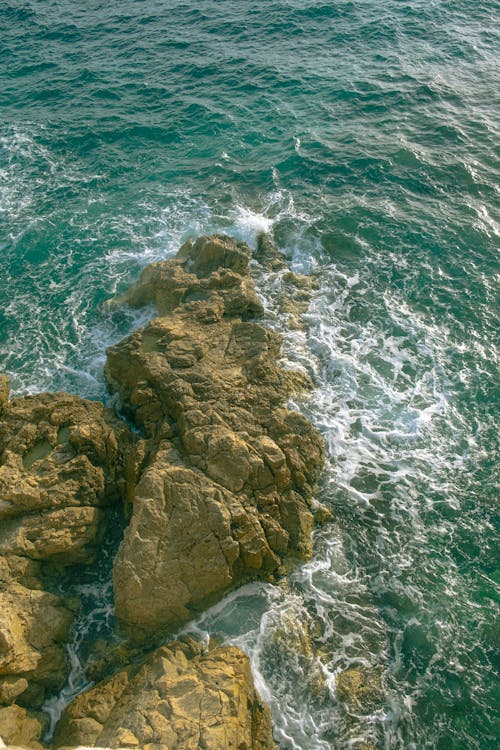 A view of the ocean from above, with rocks and waves