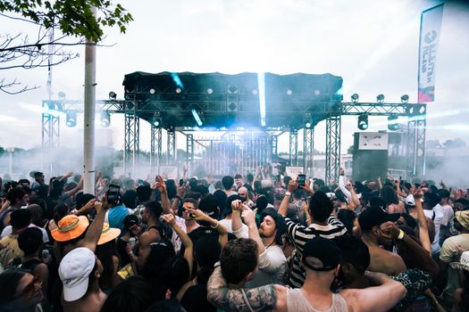 A lively outdoor music festival with a diverse crowd dancing and enjoying live performances.