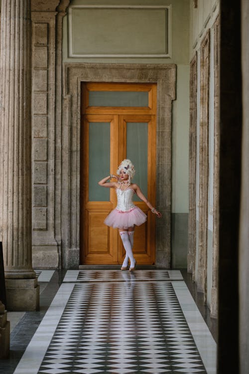 A ballerina in a pink tutu is walking down a hallway