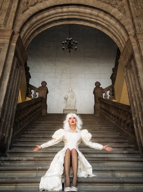A woman in a wedding dress sitting on some stairs
