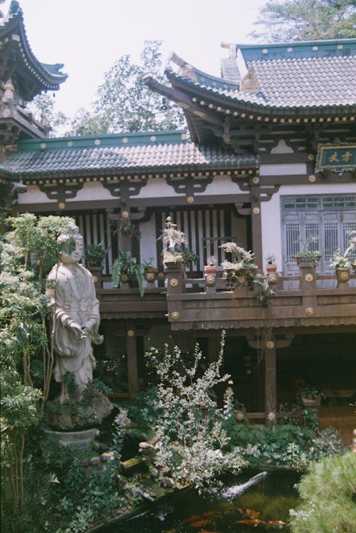 A chinese style building with a statue and a pond