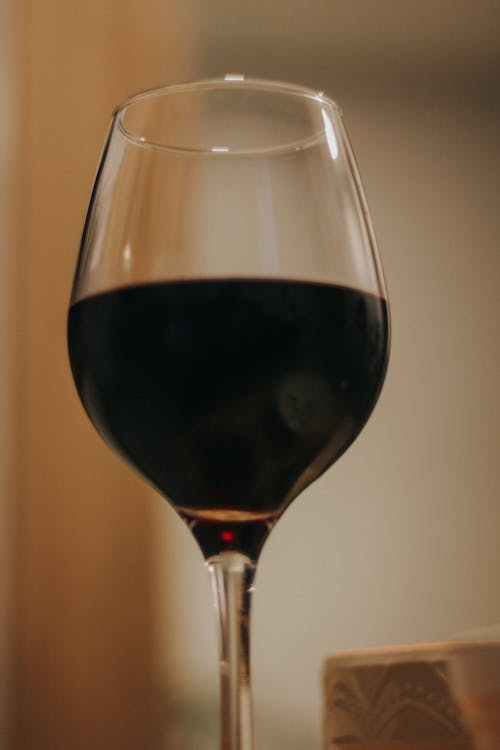 A close up of a wine glass with a red liquid