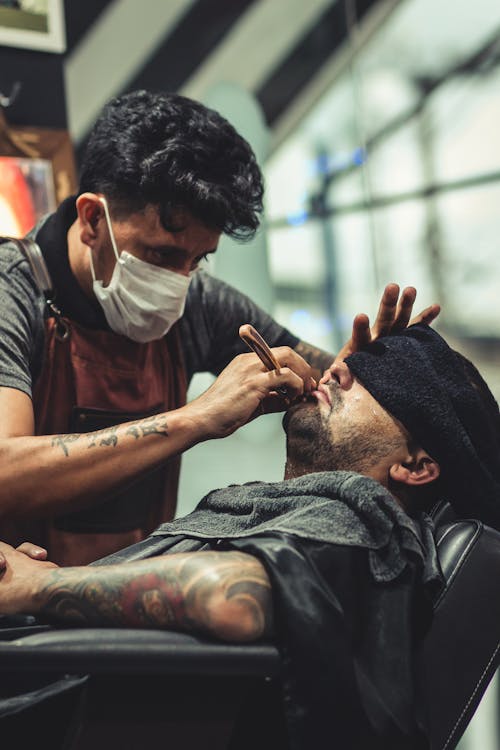 Man Shaving Man's Beard Using Straight Razor