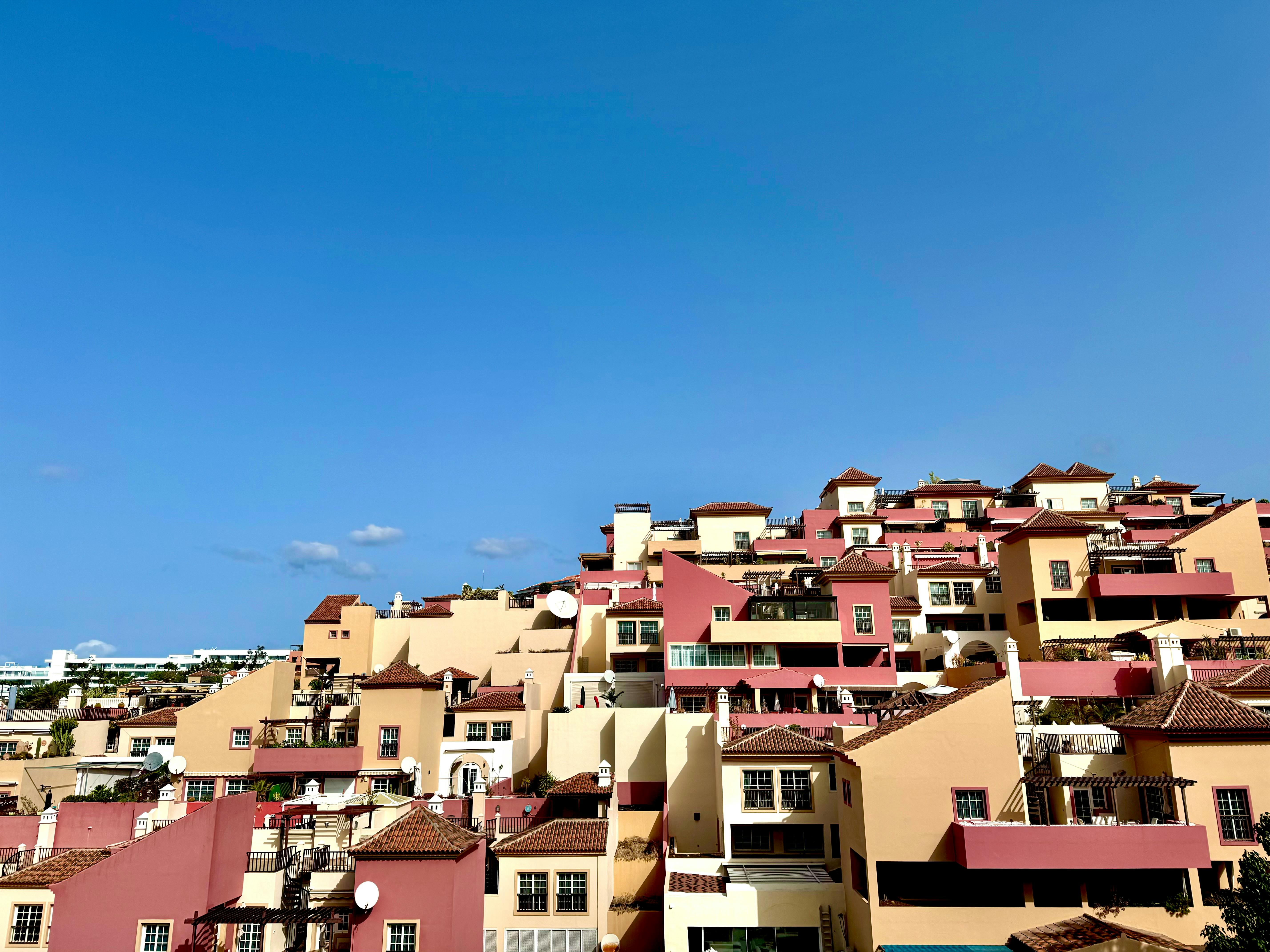 Colorful residential rooftops under clear blue sky in Costa Adeje, Spain, captured on a sunny day.