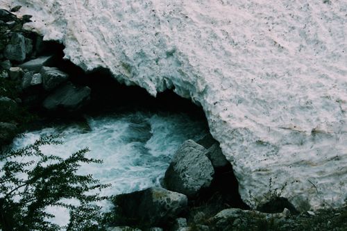 Free A scenic winter landscape of a snow-covered river flowing through rocks in Champoléon, France. Stock Photo