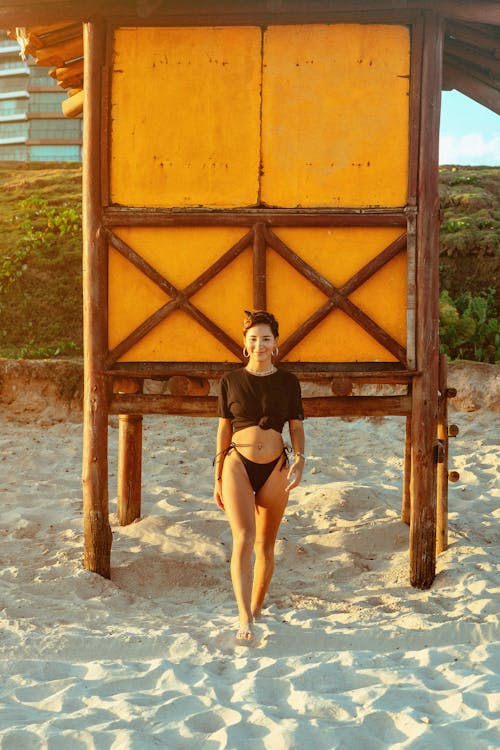 A woman in a black bikini standing on the beach