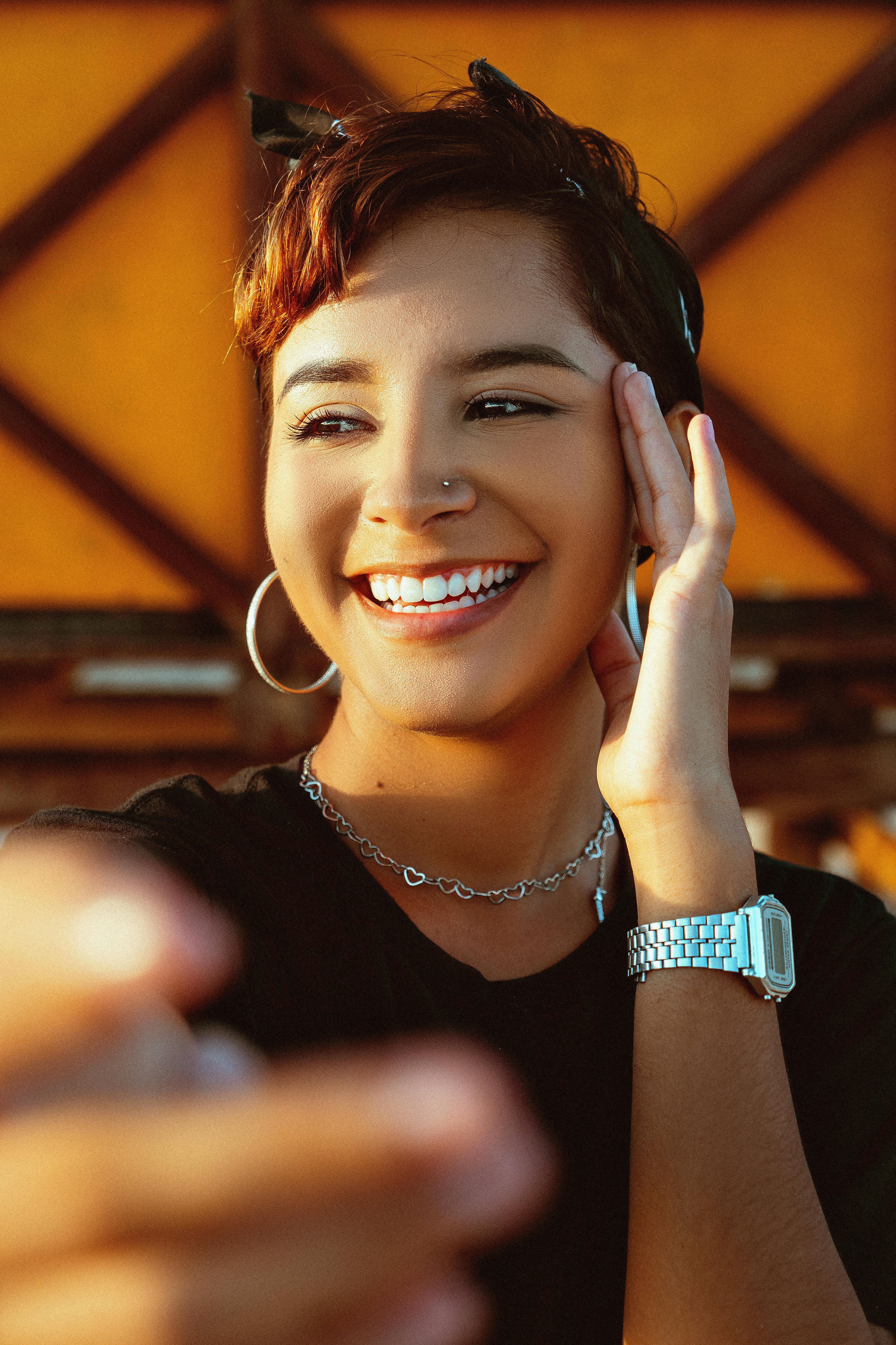 Portrait of a smiling woman with hoop earrings, enjoying outdoors.