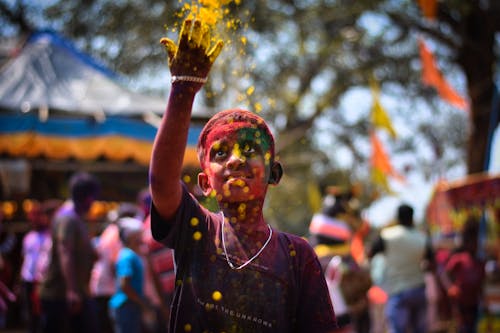 A boy is covered in colored powder at a festival