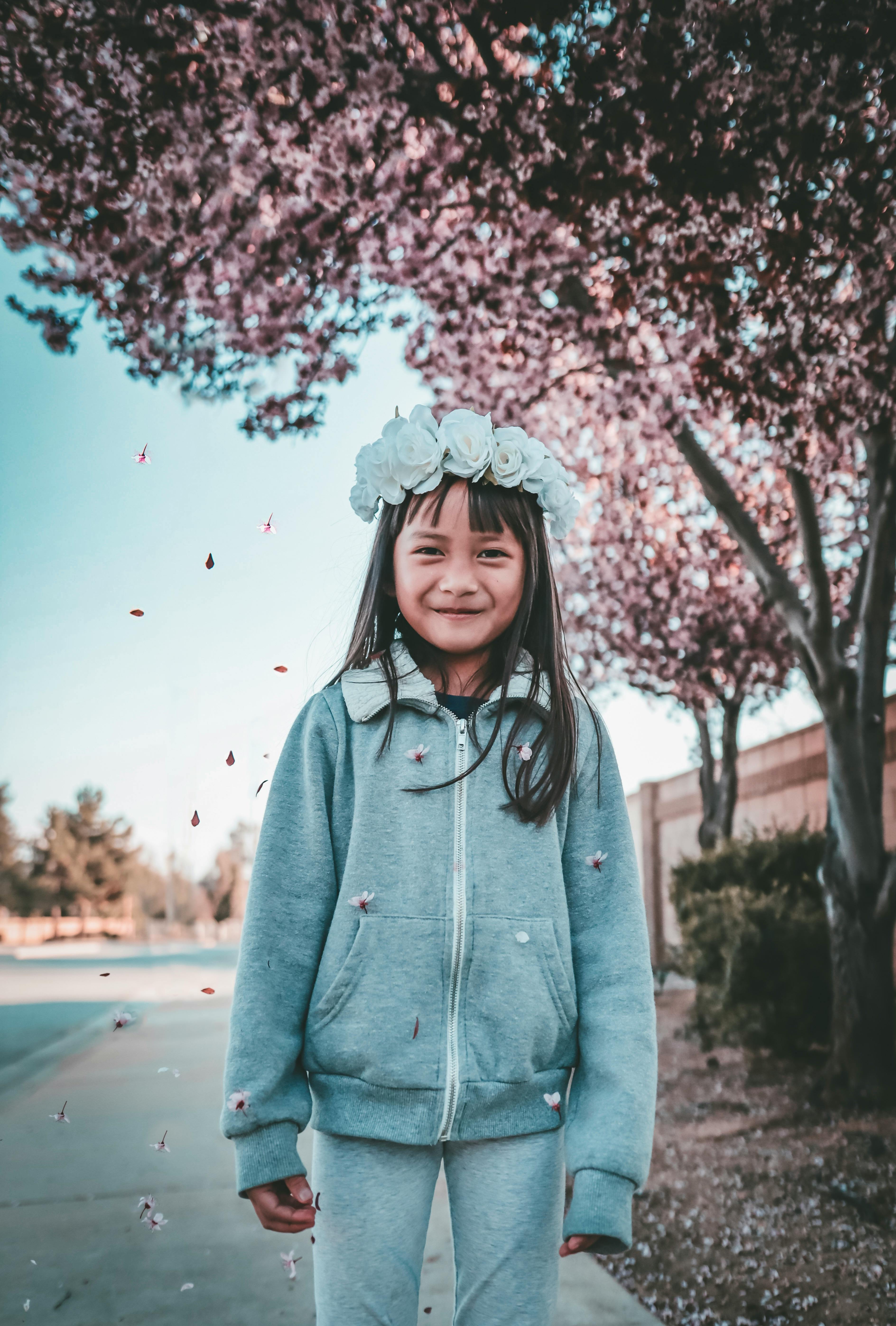 一个开朗的女孩戴着花冠，在户外欣赏春天的花朵