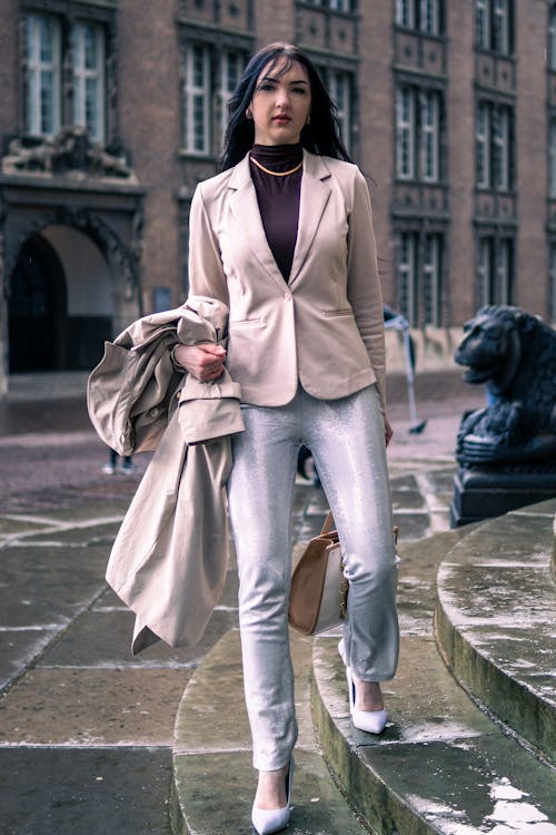 A woman in a beige jacket and white pants