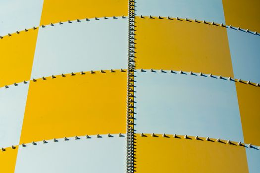 Close-up of a yellow and white checkered industrial metal structure with screws.