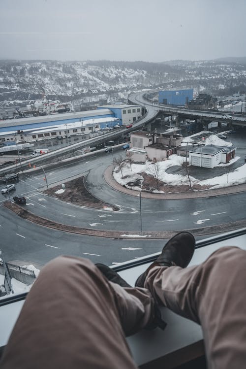 A person sitting on a window ledge looking out over a city