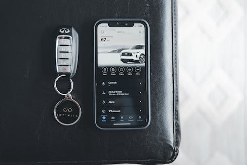 A smart phone and key fob on a black leather couch