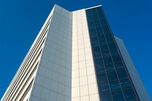 Free Close-up of a modern high-rise building facade under a clear blue sky. Stock Photo