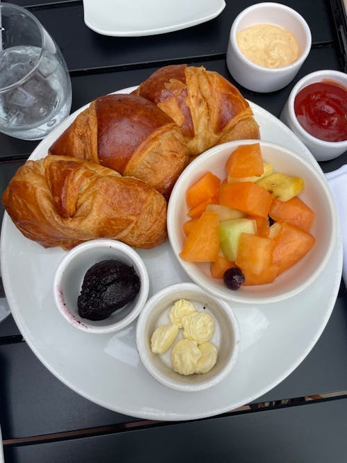 A white plate with croissants, fruit and juice