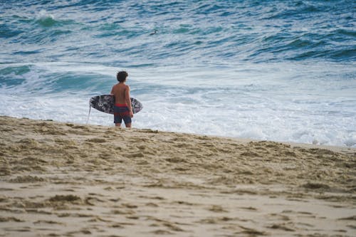 A person holding a surfboard on the beach