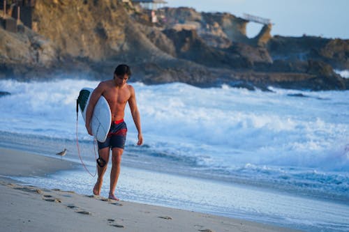 Man Carrying a Surfboard on the Beach