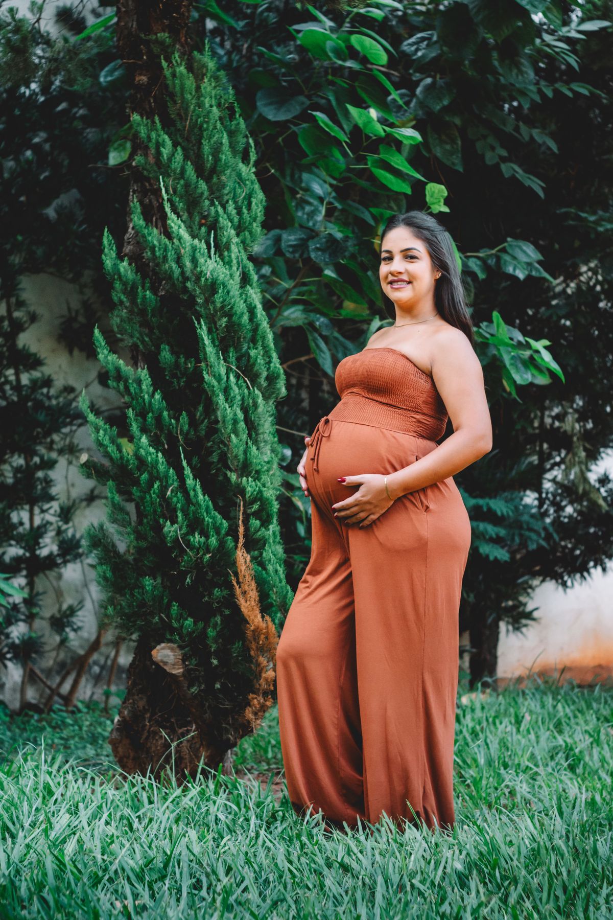 Gestante sorrindo, com as mãos sobre a barriga