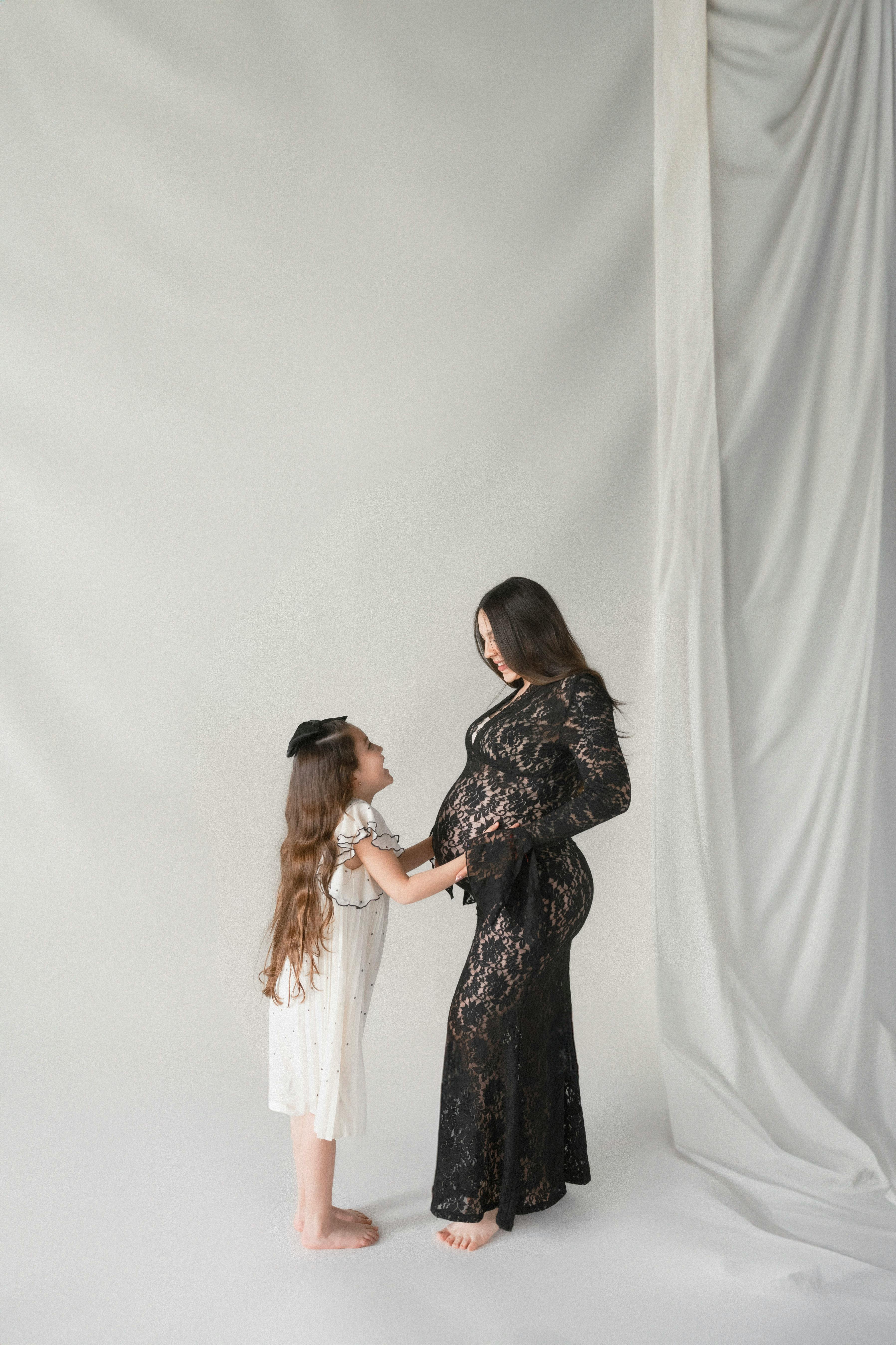 pregnant woman in black dress standing with daughter