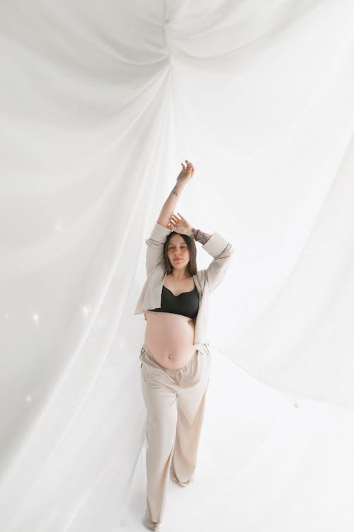 Free A pregnant woman is standing in front of a white curtain Stock Photo