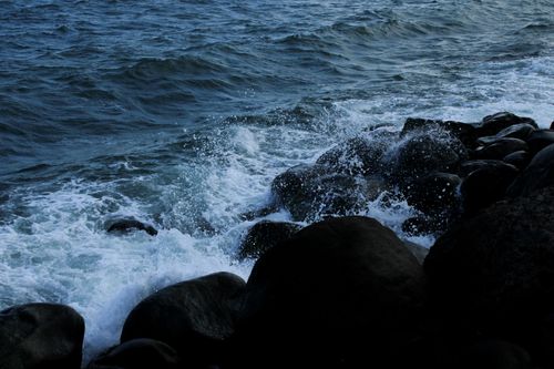 Free Waves collide powerfully against dark rocks on the Veracruz coastline in Mexico, creating a dramatic ocean scene. Stock Photo