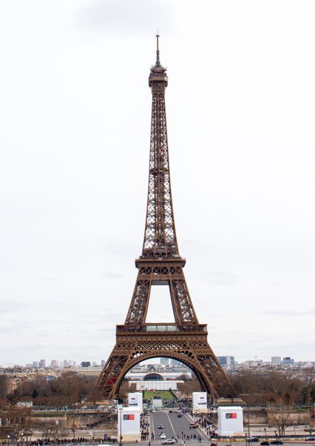 A vertical shot of the iconic Eiffel Tower against a cloudy Paris skyline.